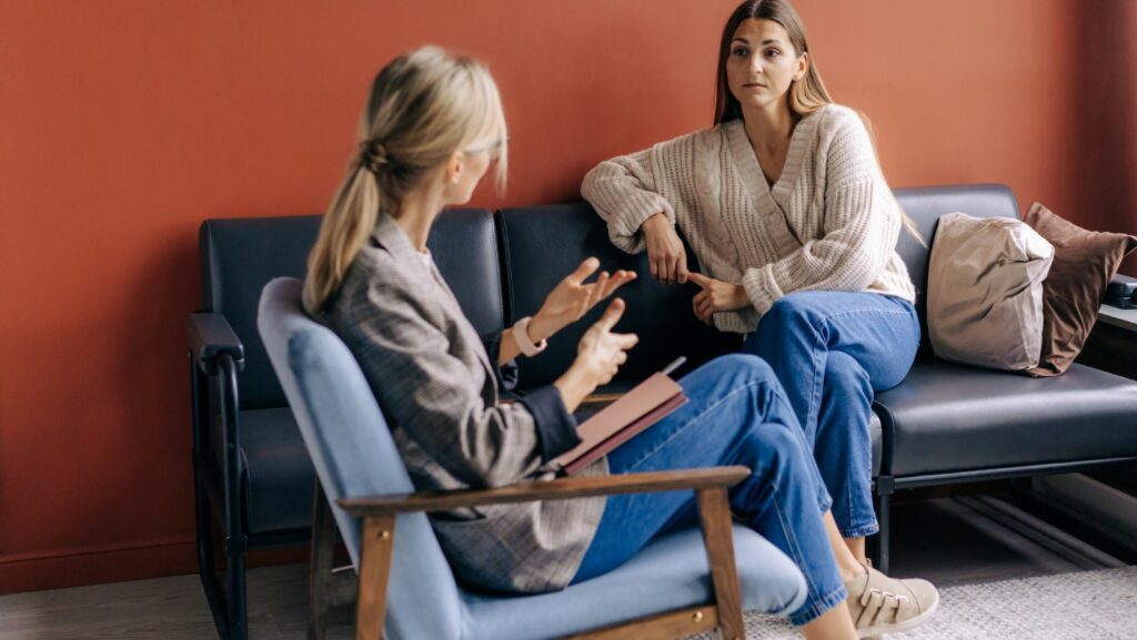 Två personer (kvinnor) sitter och diskuterar.