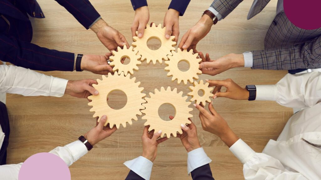 People holding cogs in the wheel. Illustrates staff as cogs in the business building process.